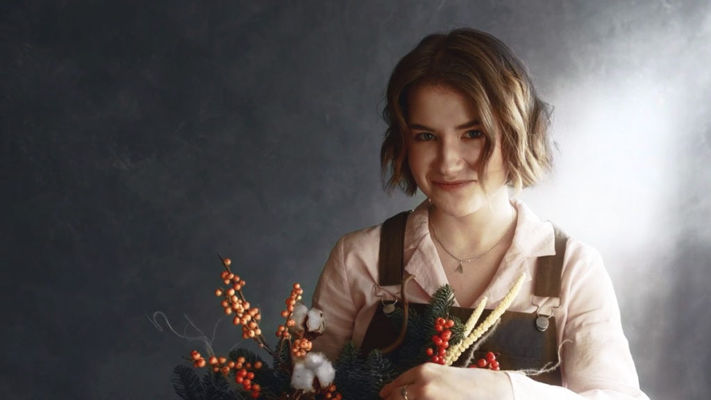 A woman holding a colorful bouquet of berries and flowers, showcasing nature's vibrant beauty.