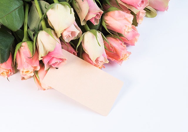 A bunch of pink roses with a blank card on top, perfect for expressing your heartfelt sentiments.