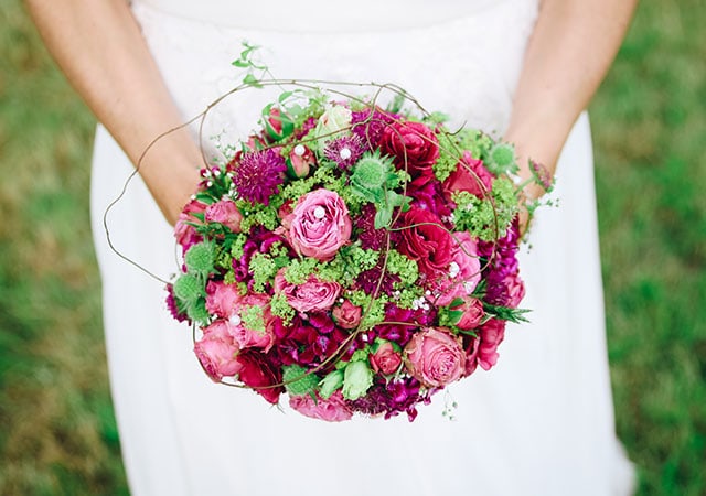 A bride holding a bouquet of pink flowers, radiating elegance and joy on her special day.